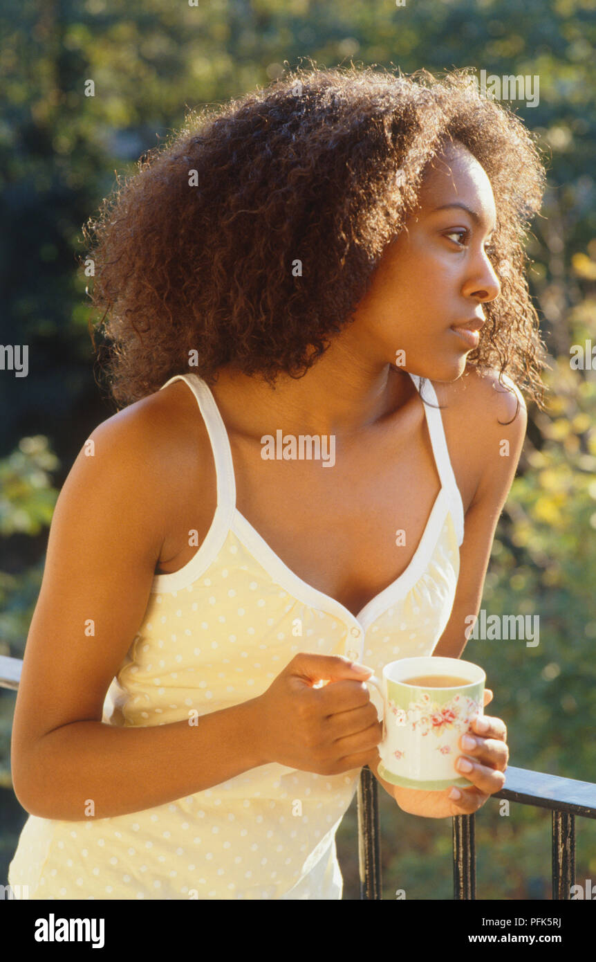 Woman on balcony holding cup of tea Stock Photo