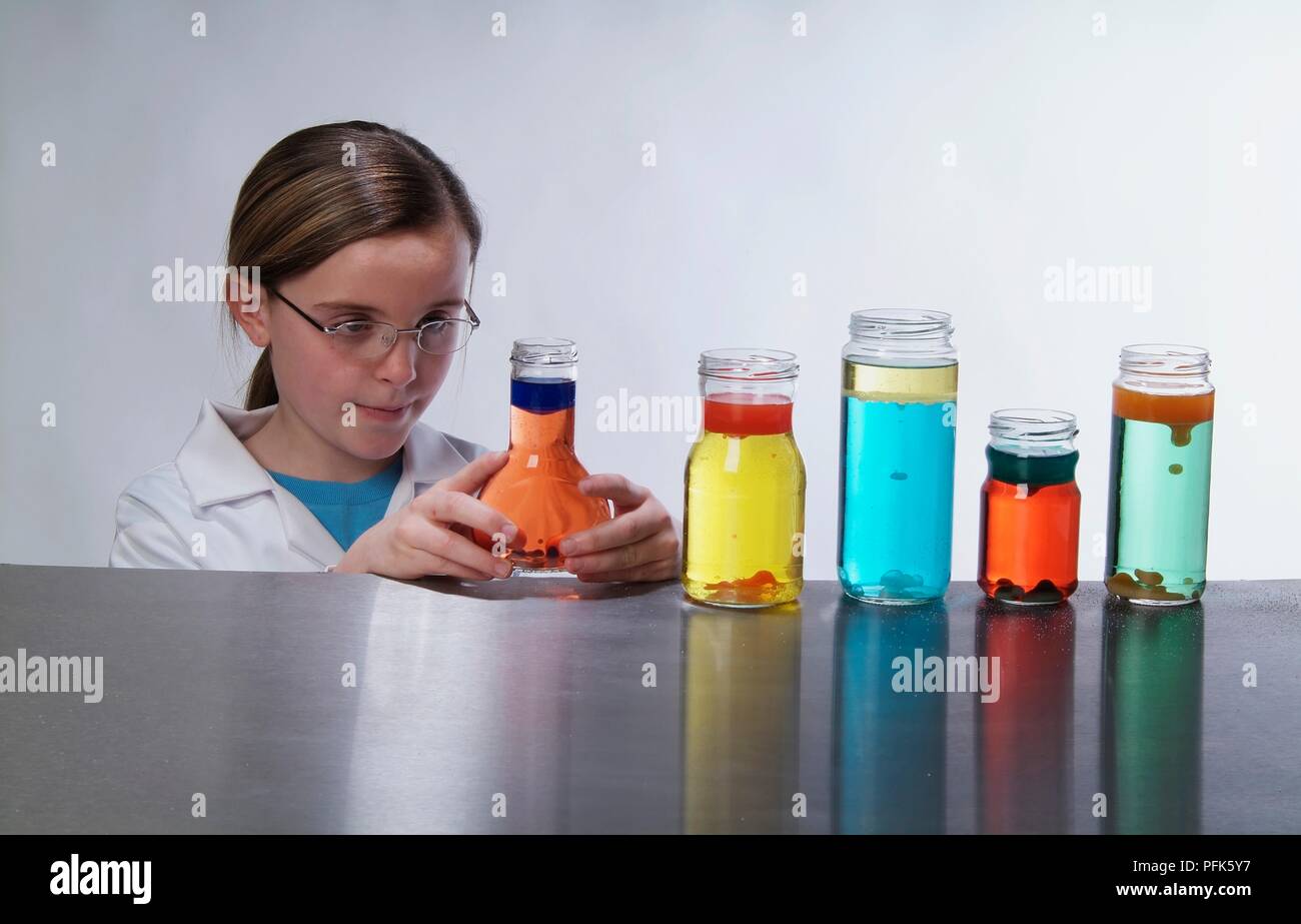 Girl looking at bottle containing orange liquid Stock Photo