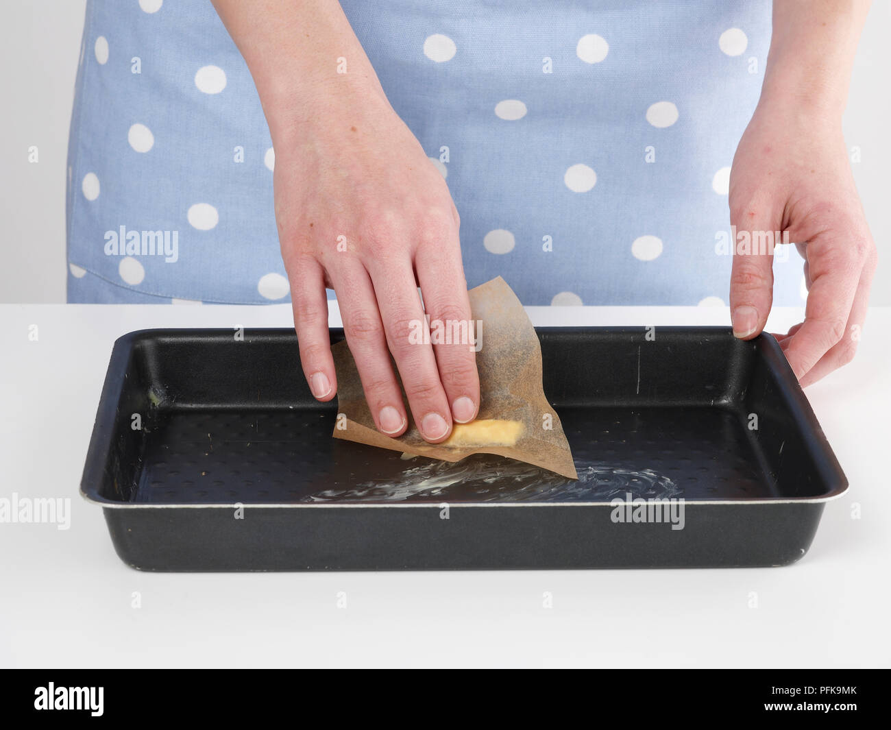 Young woman's hands greasing cake tin with butter, close-up Stock Photo