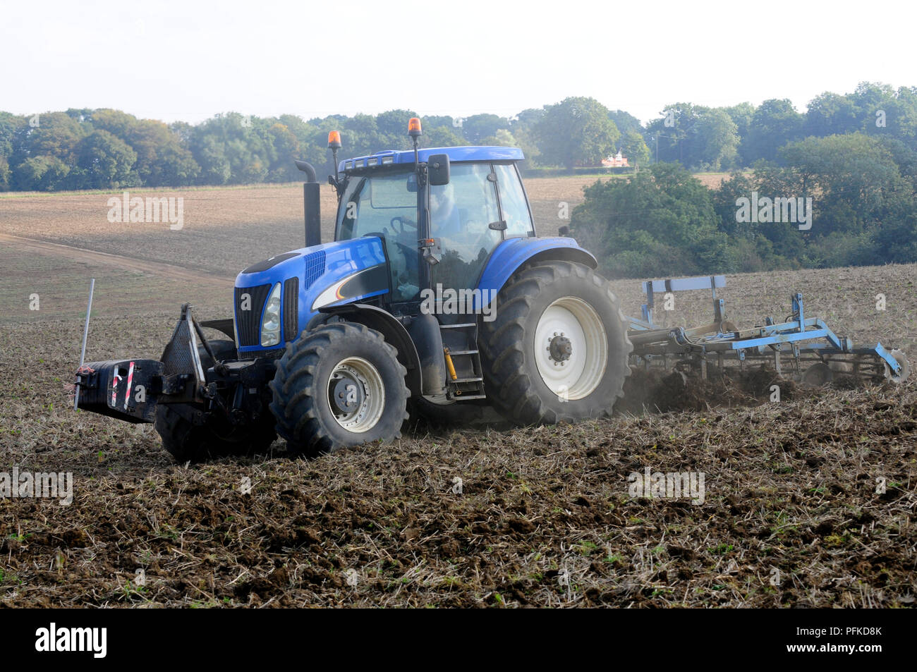 Blue tractor ploughing field, side view Stock Photo - Alamy
