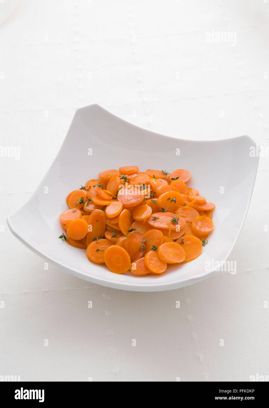 Bowl of glazed carrots with thyme, close-up, high angle view Stock Photo