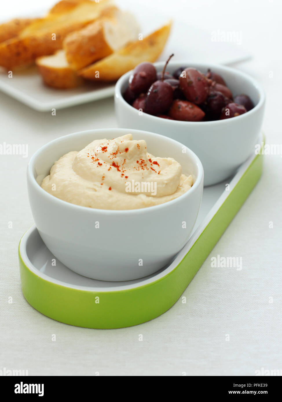 Bowl of Taramasalata, dip made from cod's roe, served with bowl of black olives and sliced white bread, close-up Stock Photo