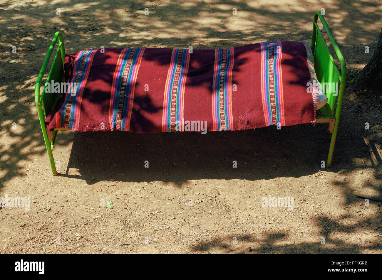 Village lifestyle, one old vintage style bed on dirty ground in the middle of the wood, during day. Stock Photo