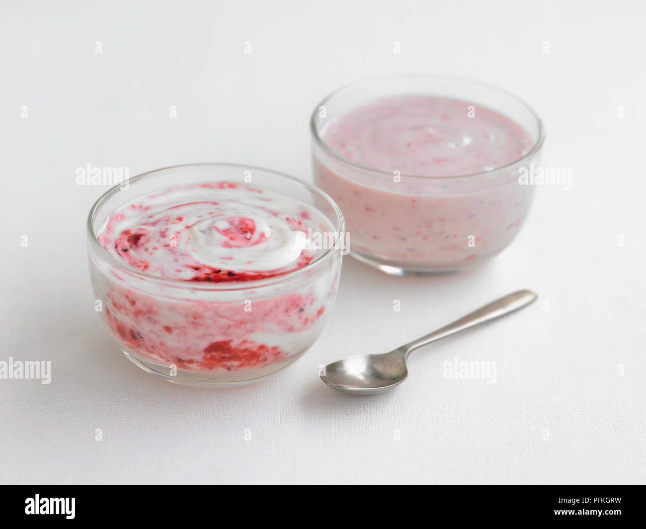 Raspberry yogurt in glass bowls with teaspoon Stock Photo Alamy