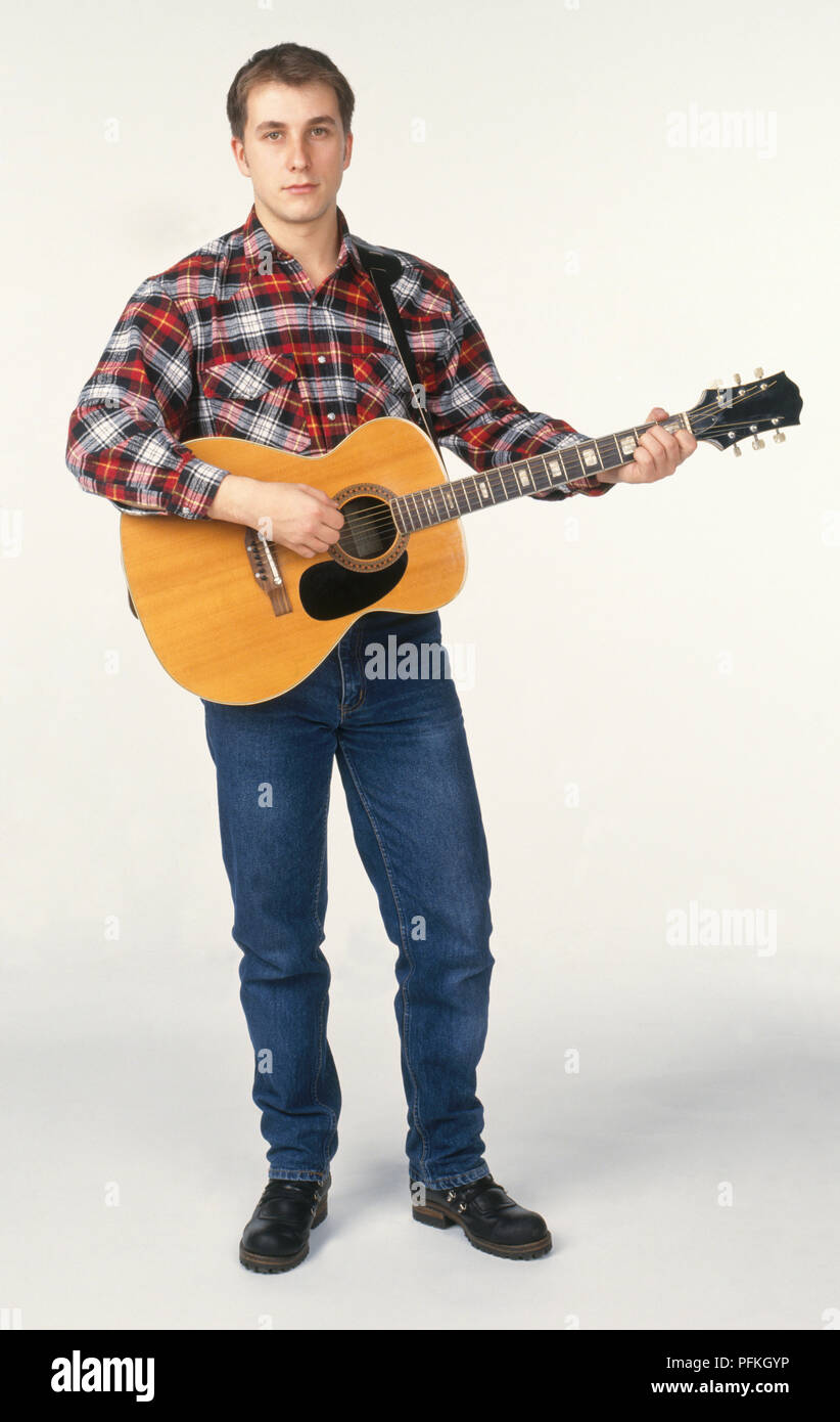 Young man holding acoustic guitar, front view Stock Photo - Alamy