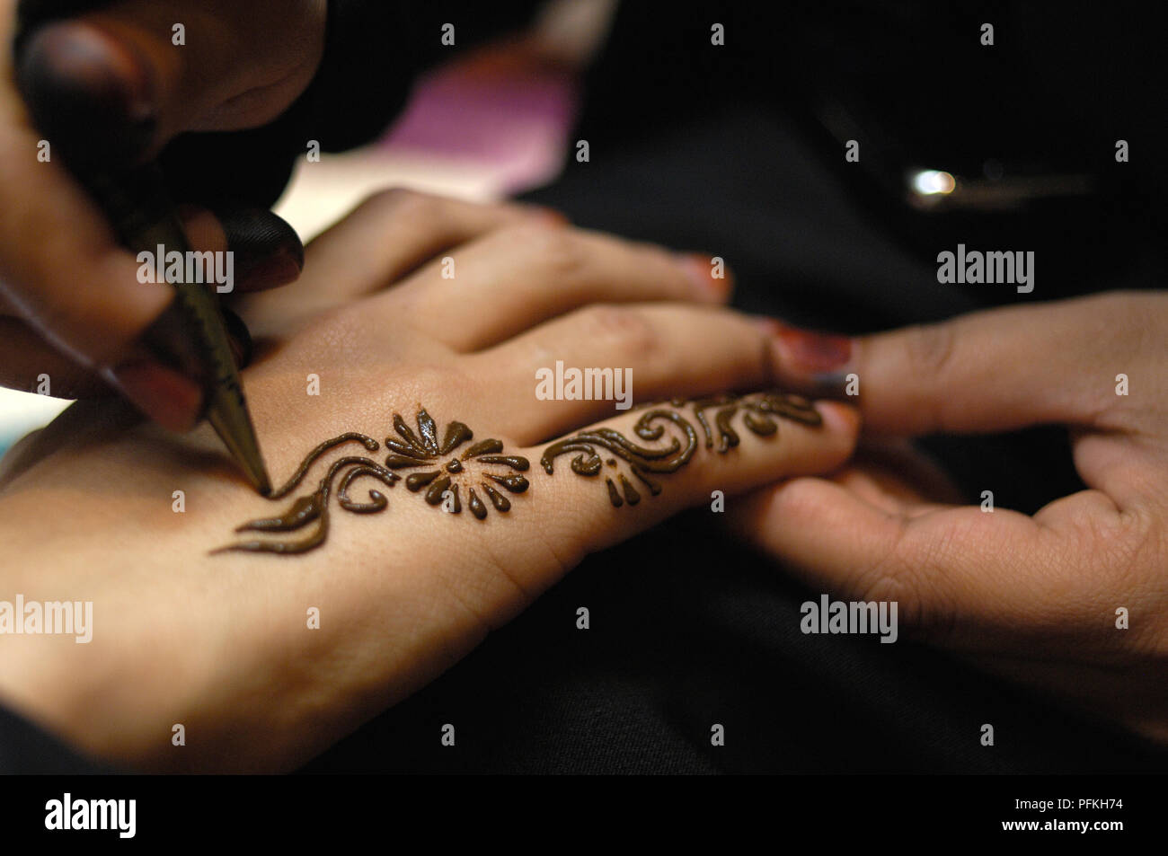 United Arab Emirates, Dubai, applying henna pattern to woman's hand