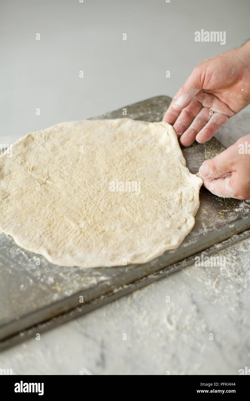 Hands stretching pizza dough into shape, close-up Stock Photo