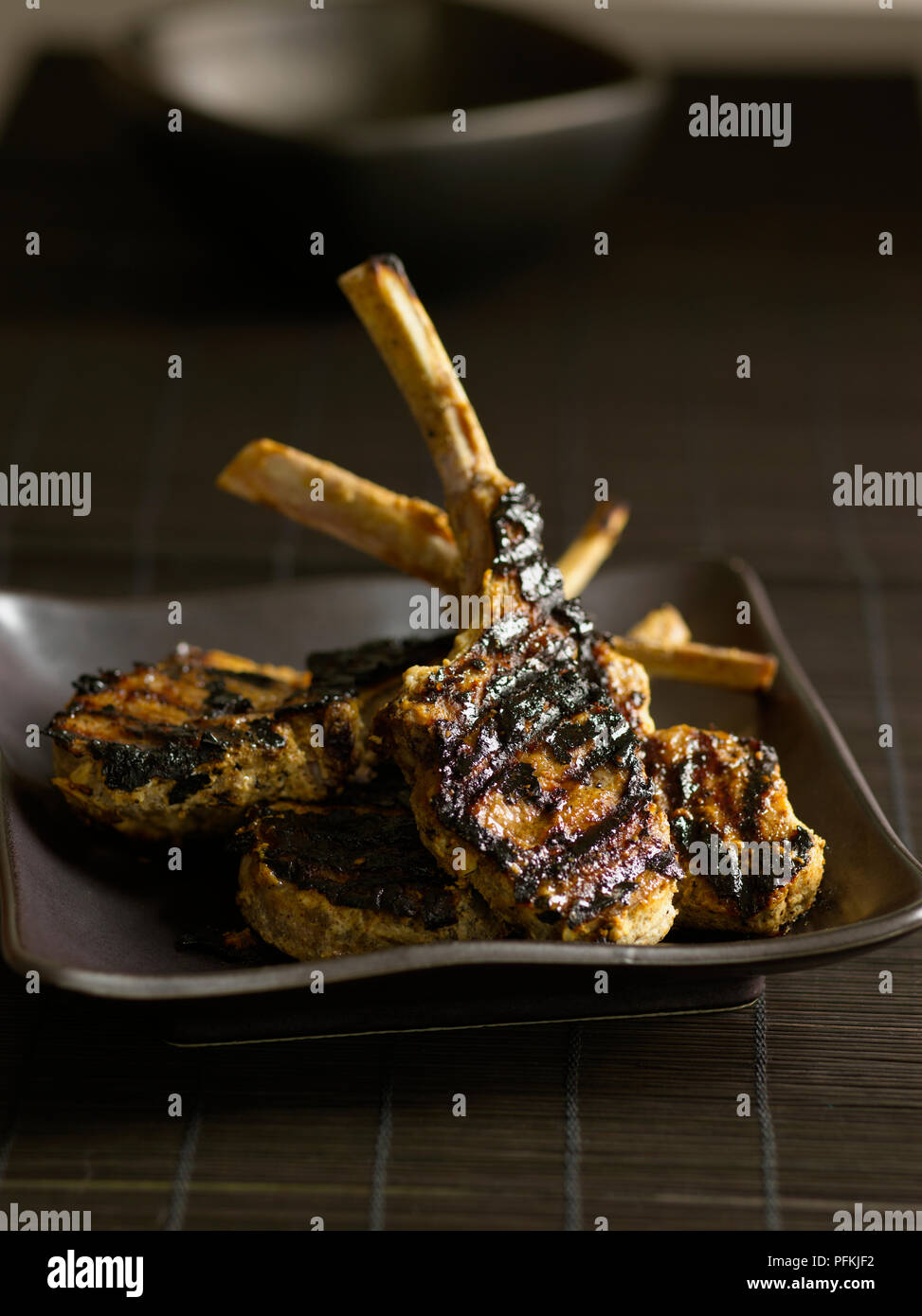 Lamb lollipops, marinated and grilled lamb rib chops, on brown plate Stock Photo