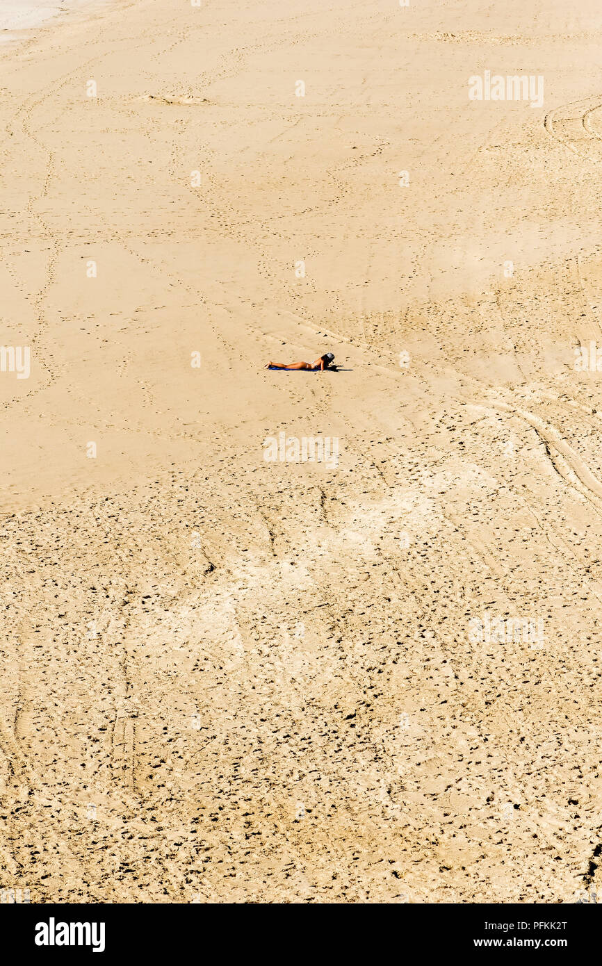 woman sunbathing alone on a deserted beach Stock Photo