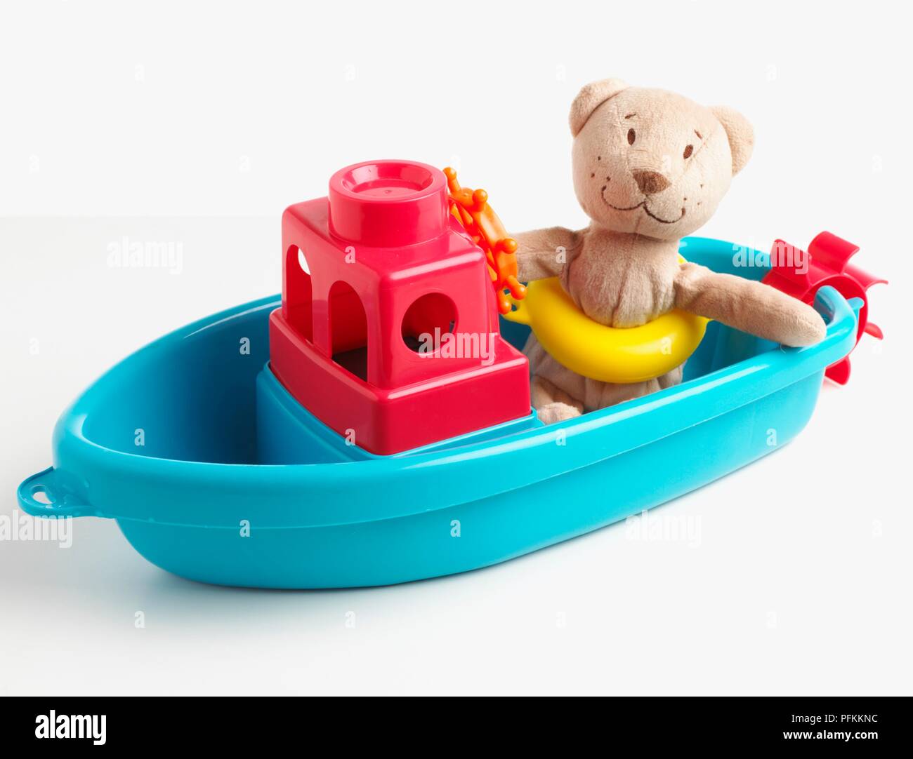 Teddy bear wearing life belt sitting in plastic boat Stock Photo