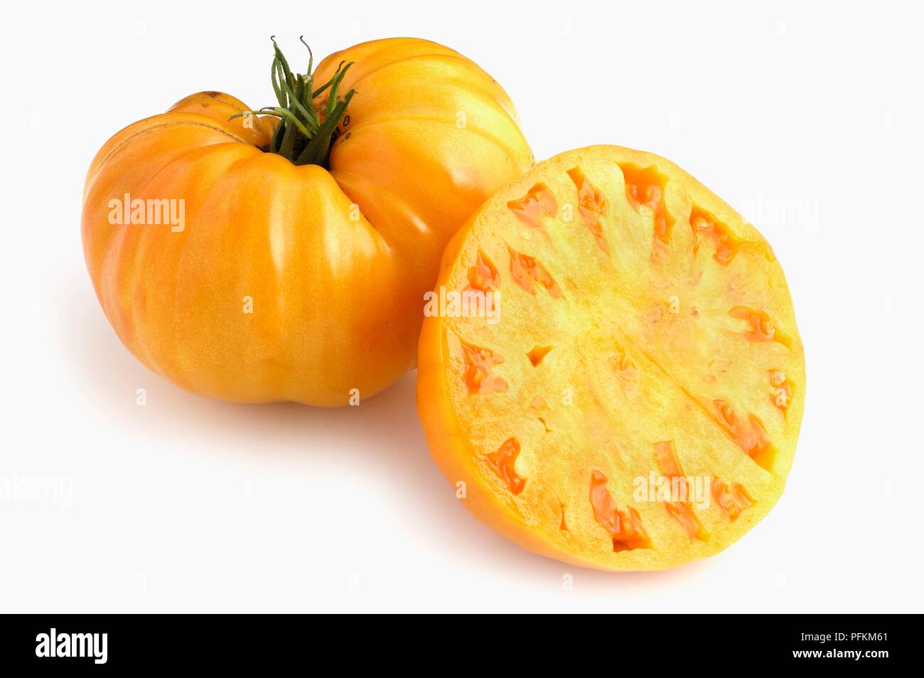Whole and sliced American Yellow Oxheart tomato Stock Photo
