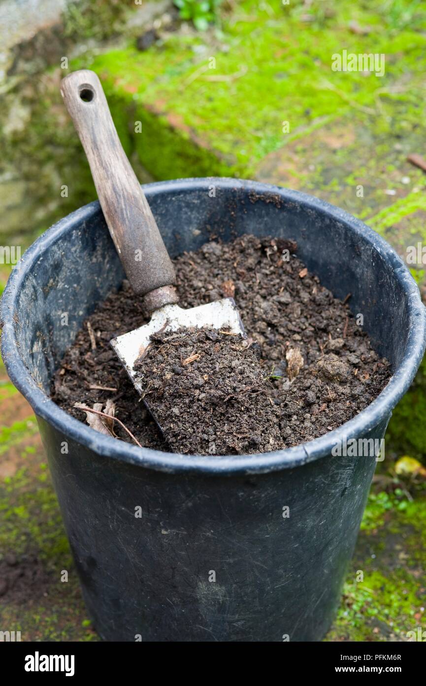 Trowel in large plastic plant pot containing soil and compost Stock Photo