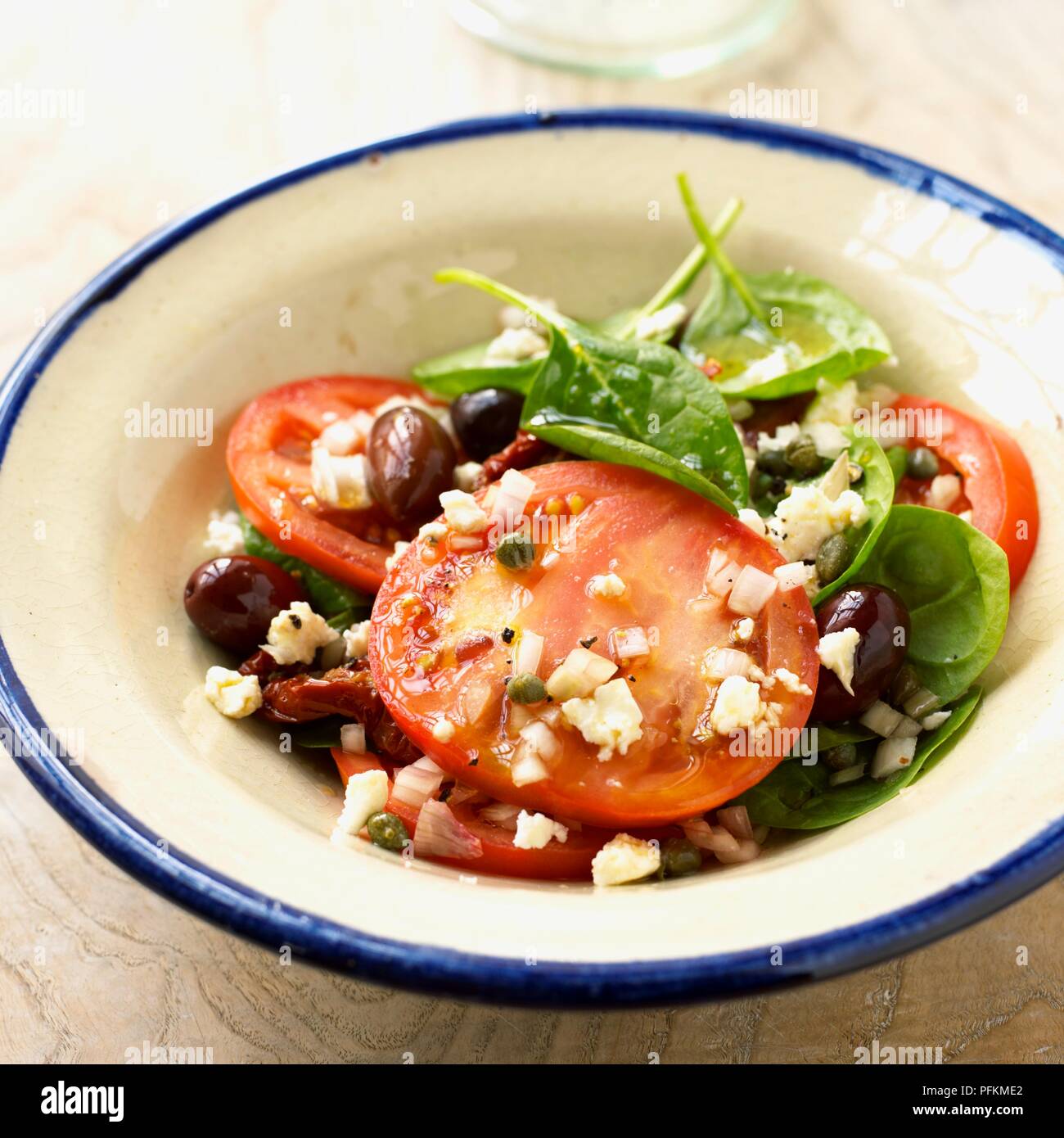 Melted feta on sliced beefsteak tomatoes with spinach Stock Photo