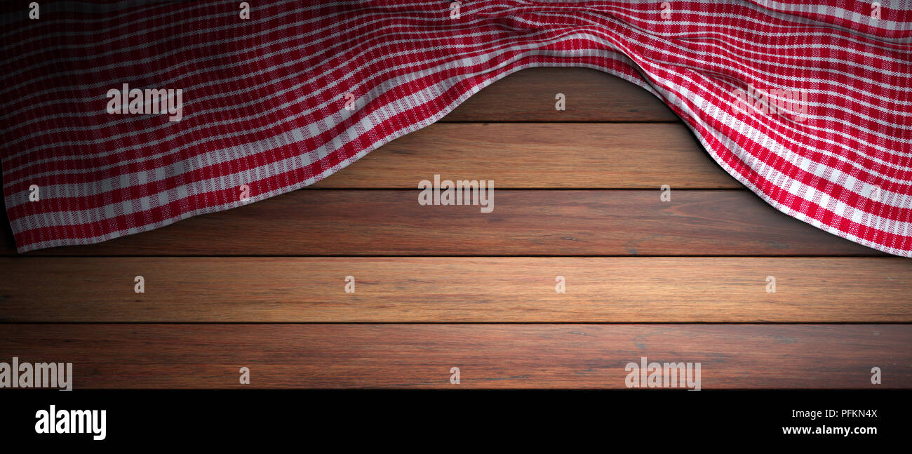 Red and white checkered picnic tablecloth on wooden background, copy