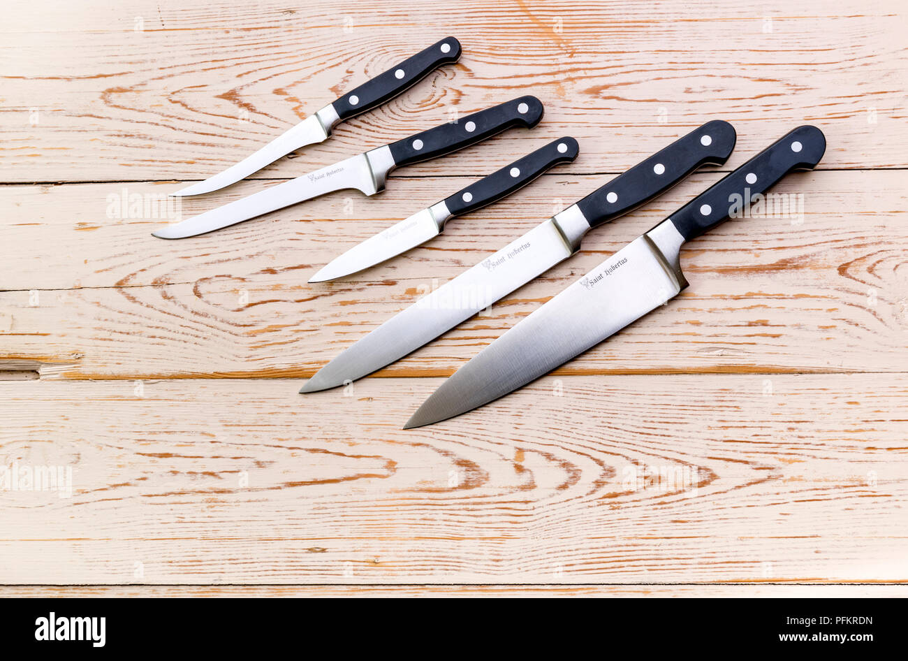 An assortment of various kitchen knives on a wooden background. Stock Photo