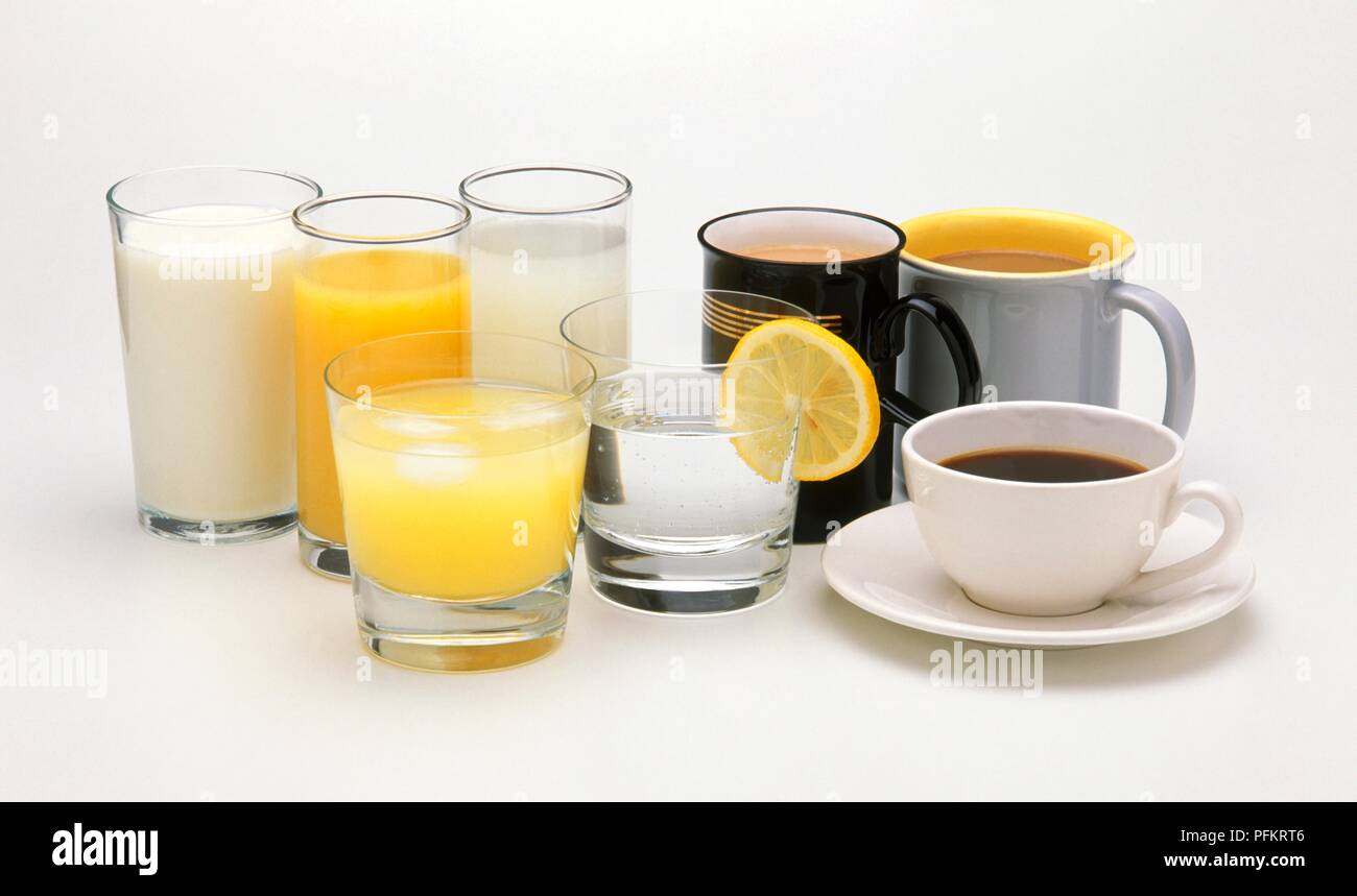 Mugs and cup of tea and coffee next to glasses of water, milk and fruit juice Stock Photo