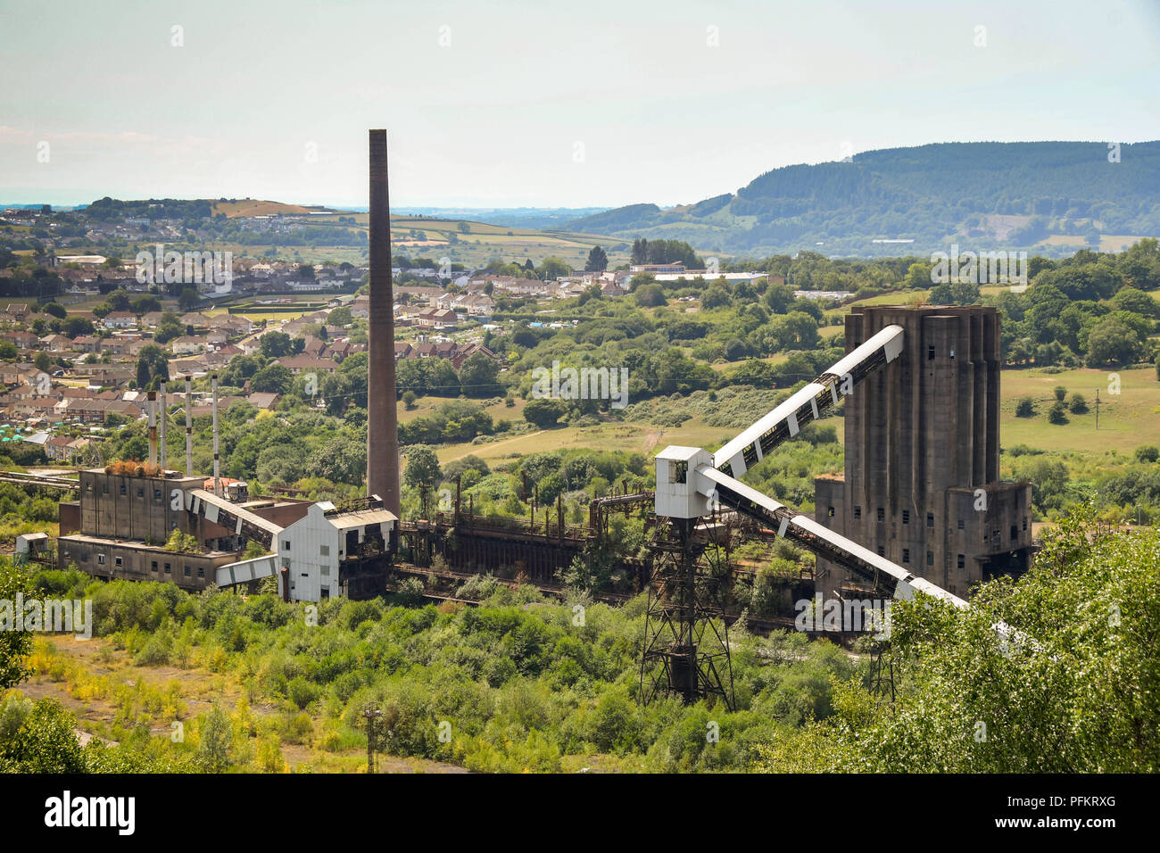 Derelict buildings  and chimney stack on the site of the former Cwm colliery and coke ovens in Beddau near Pontypridd, Wales. Stock Photo