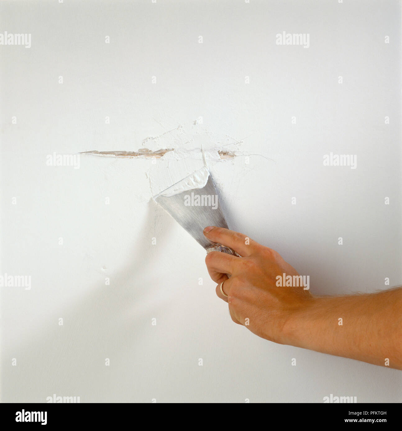 Person Filling Crack In Wall With Fresh Plaster Using