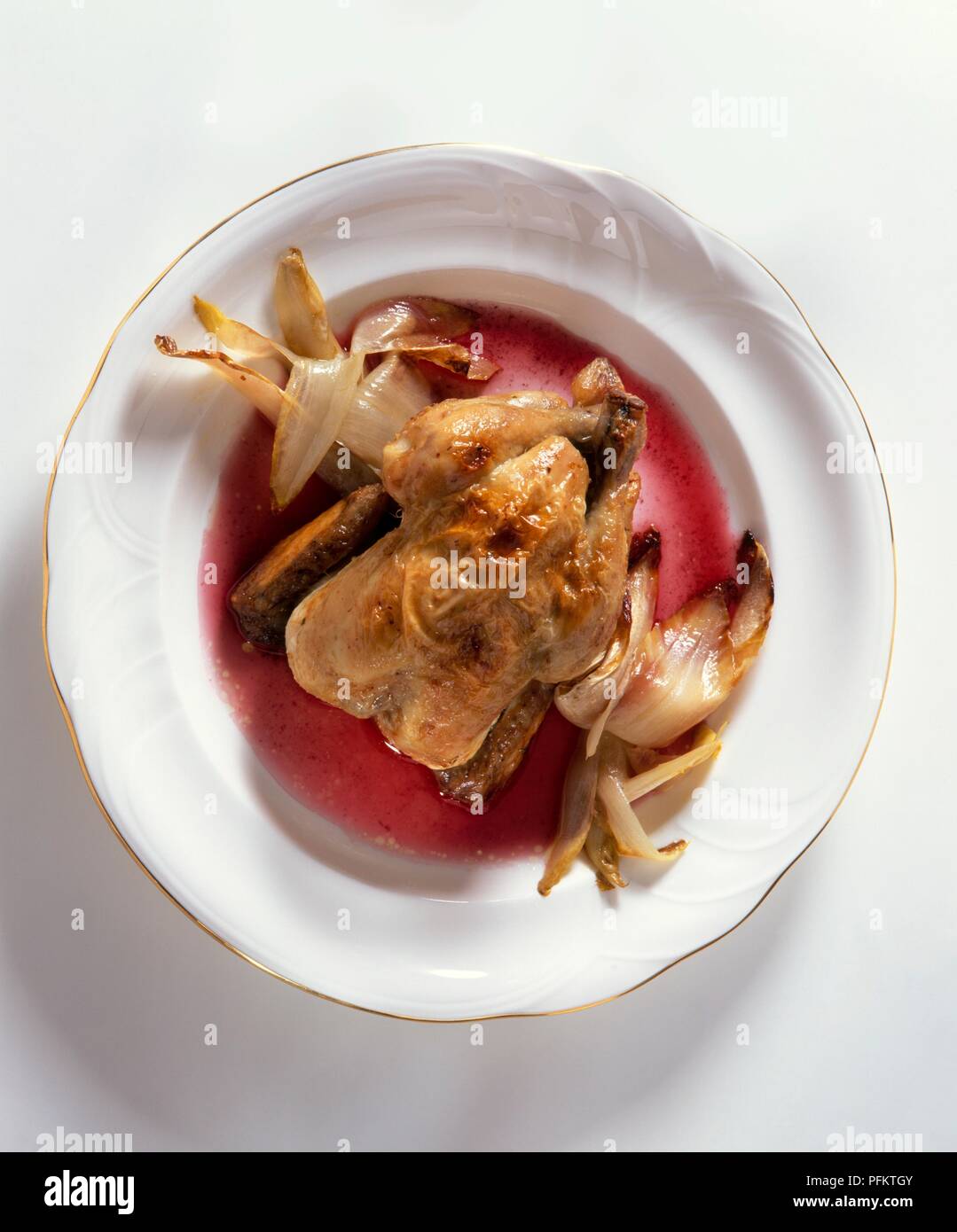 Poussin with braised chicory and red vinegar sauce, served on a plate Stock Photo
