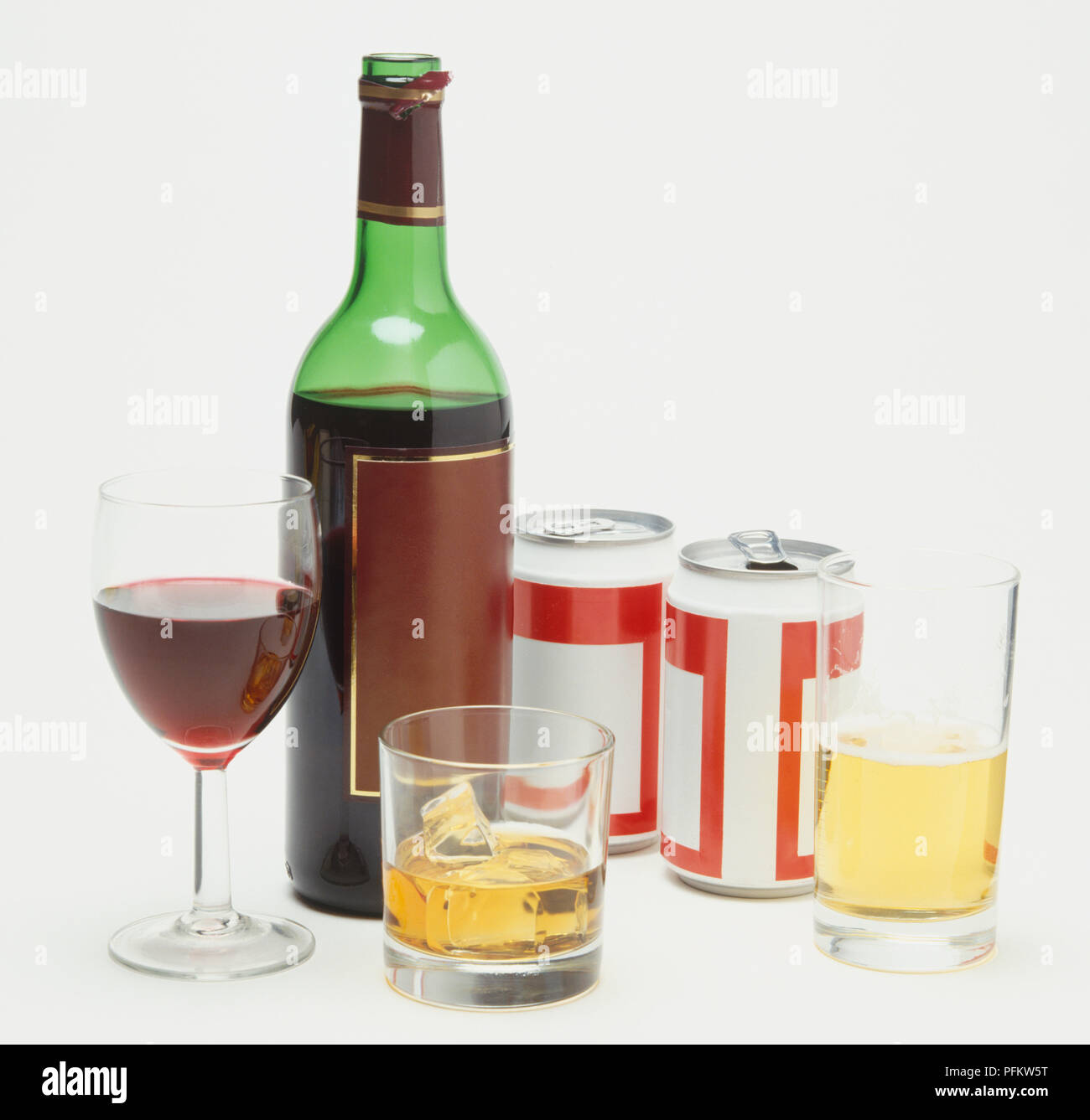 Selection of alcoholic drinks including bottle and glass of red wine, two tins of beer and glass half filled with beer, whisky glass containing ice cubes. Stock Photo