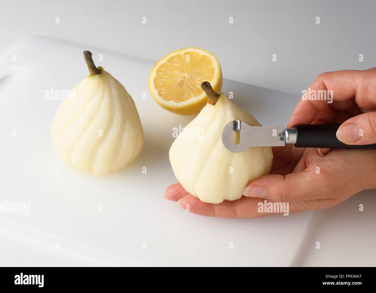 Cutting spiral stripes into peeled pears, using canelle knife, closeup