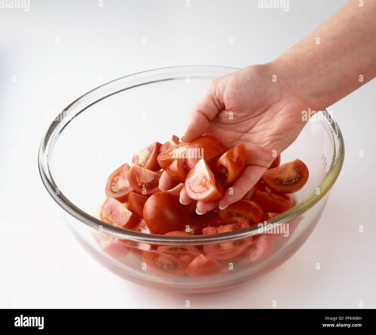 Hand holding sliced red tomatoes in glass bowl Stock Photo - Alamy
