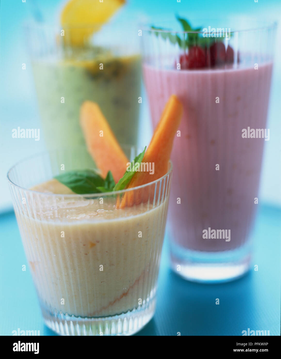 Colourful fruit smoothies in glasses decorated with basil leaves and
