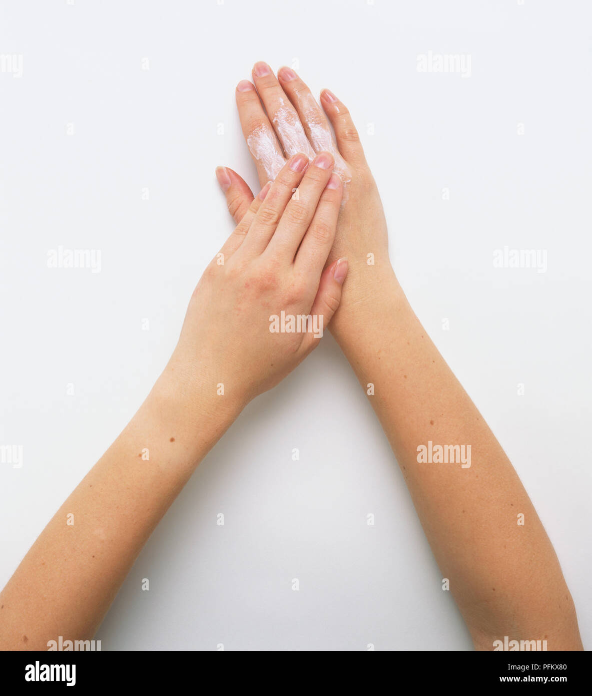 Applying emollient cream to upper side of hand, using fingers, overhead view. Stock Photo