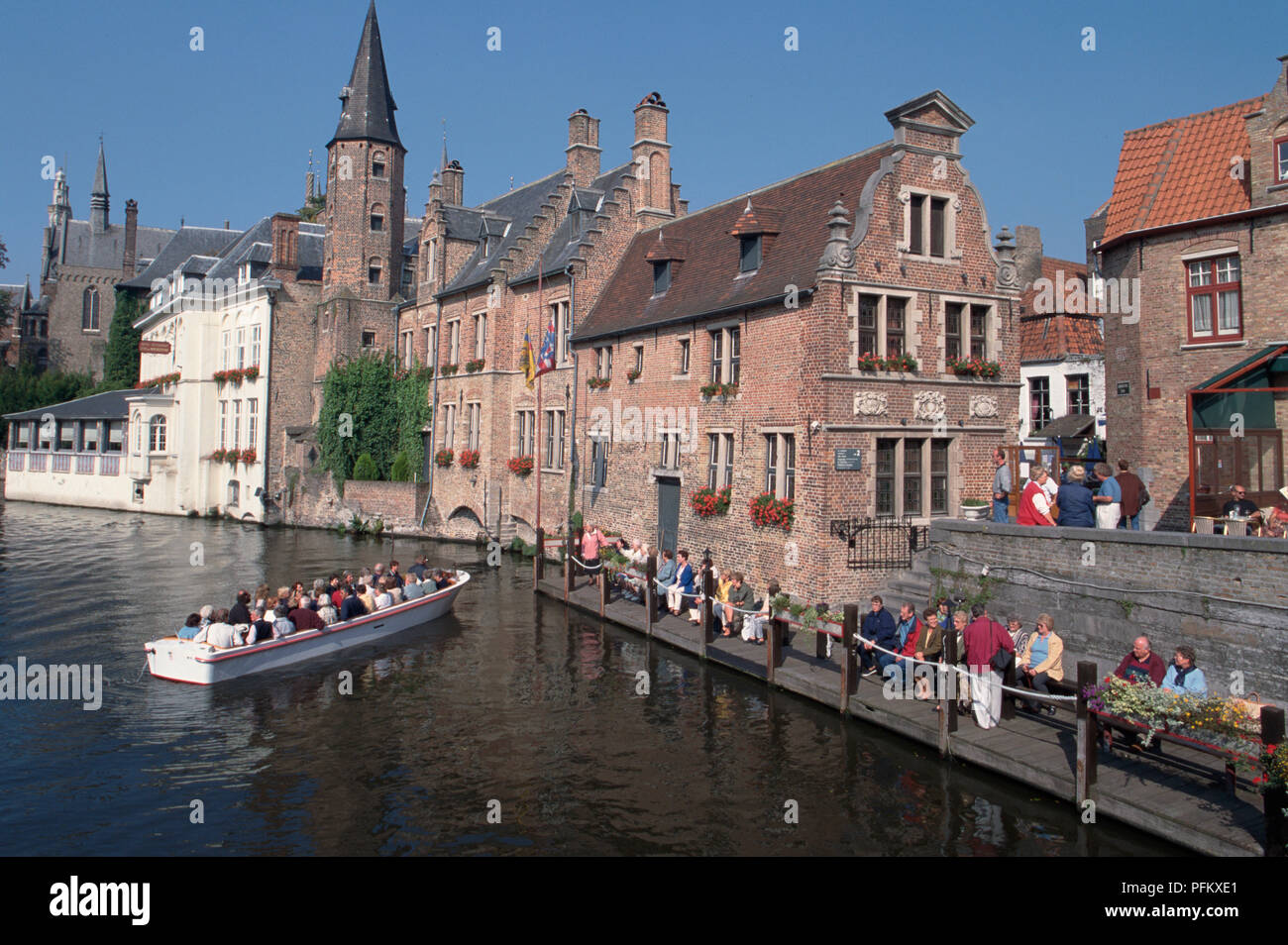 Belgium, Bruges, medieval houses line the River Dijver, with boat sailing along the river Stock Photo