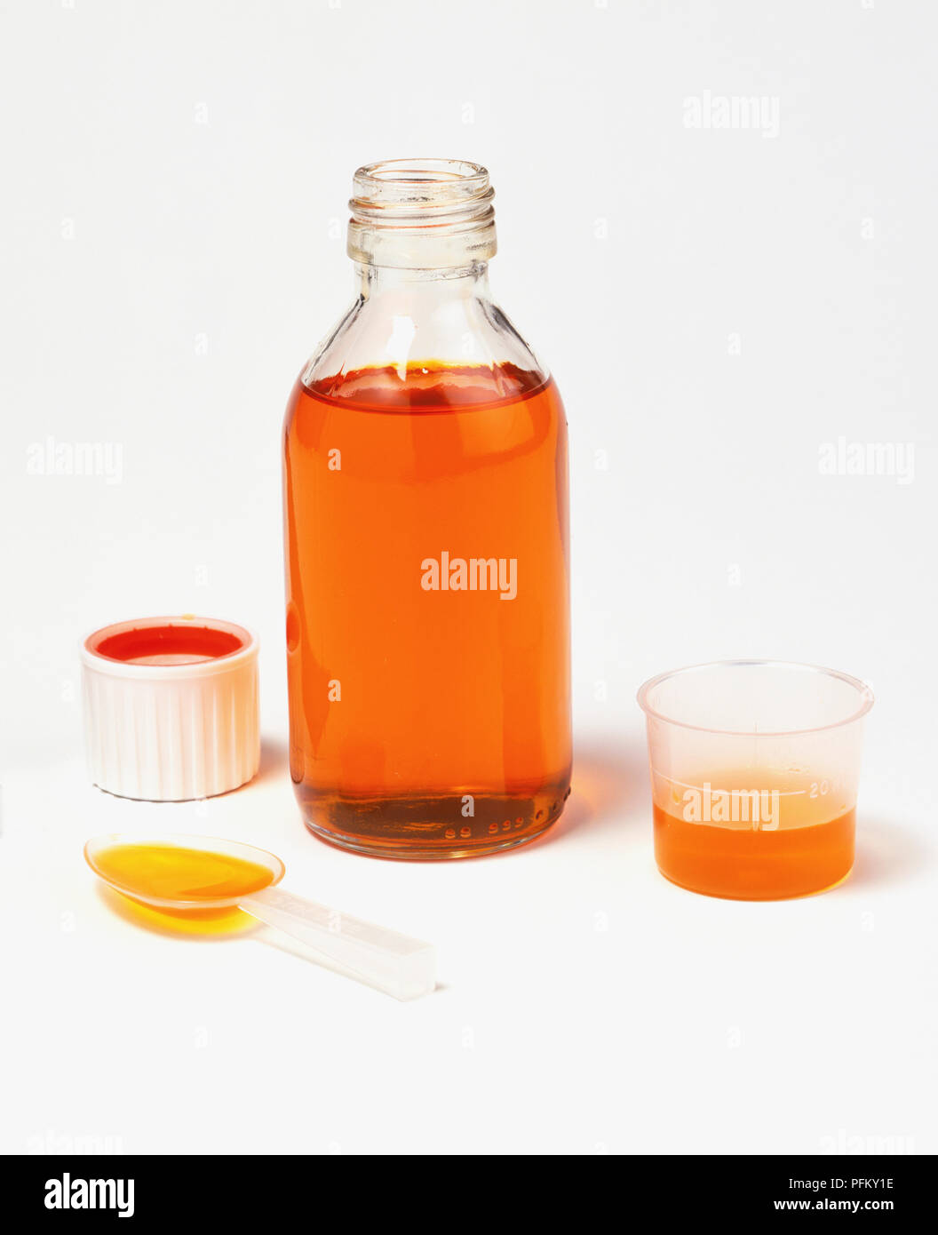 Orange liquid medicine in a plastic measuring cup, plastic spoon and