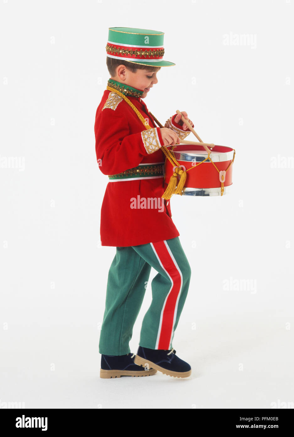 Side view of a boy wearing a marching band uniform, playing drum Stock