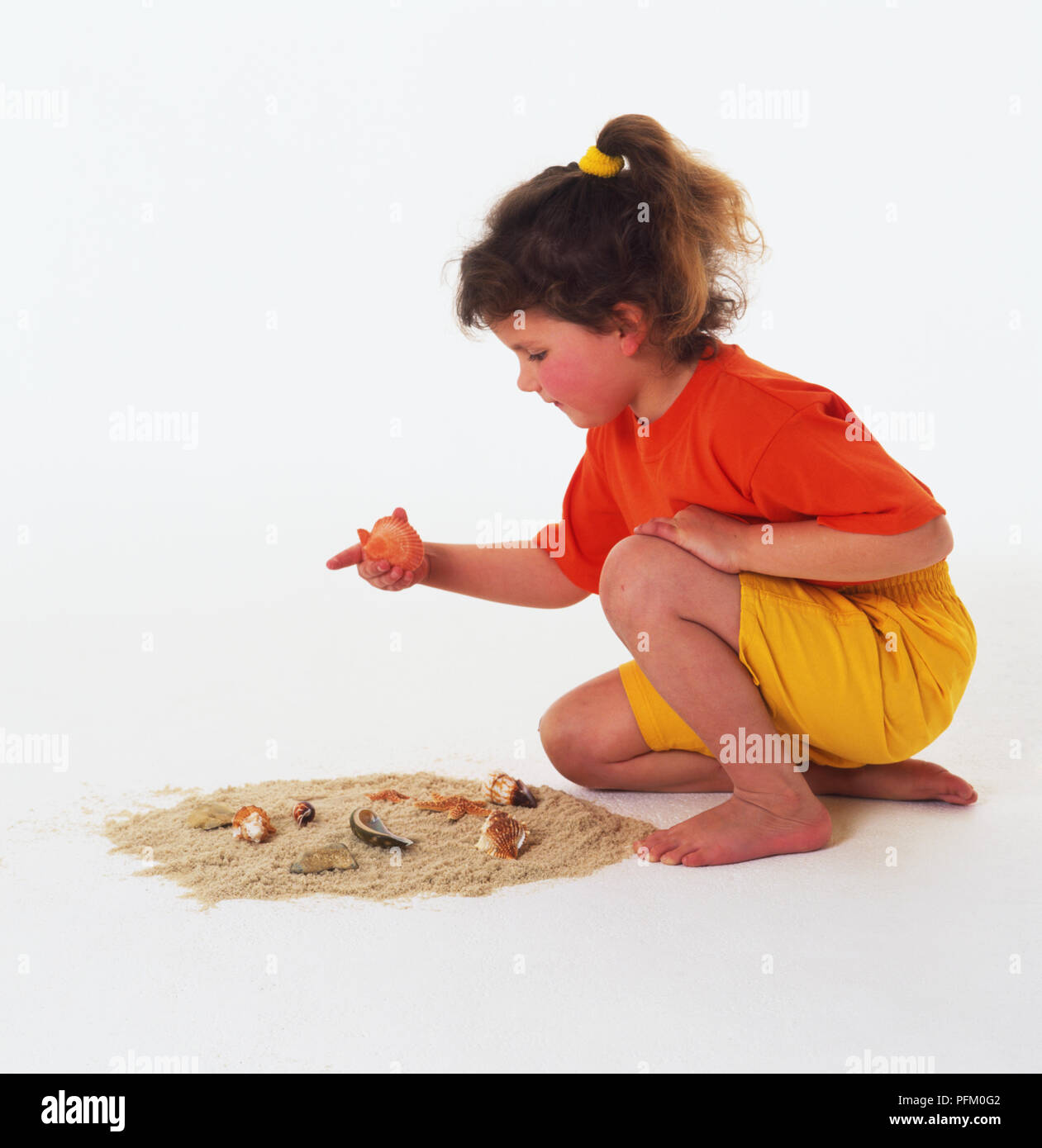 Girl kneeling in the sand hi-res stock photography and images - Alamy
