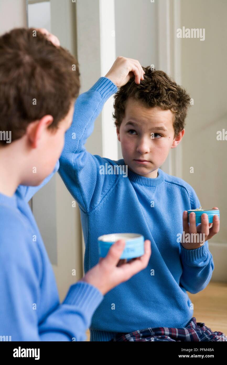 Boy applying hair wax while looking in mirror Stock Photo Alamy