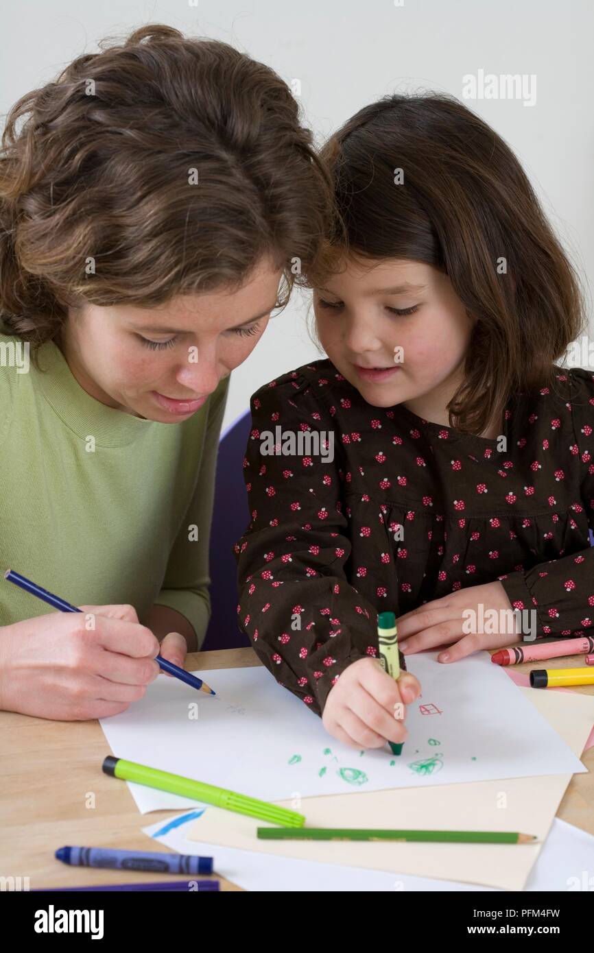Girl drawing with crayon, woman sitting next to her drawing with