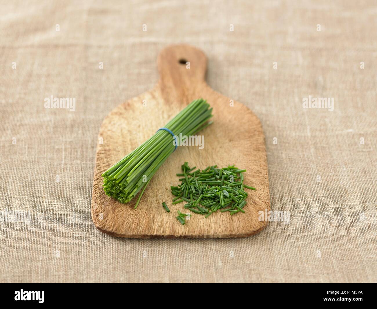 Chopped and whole chive stems on chopping board Stock Photo