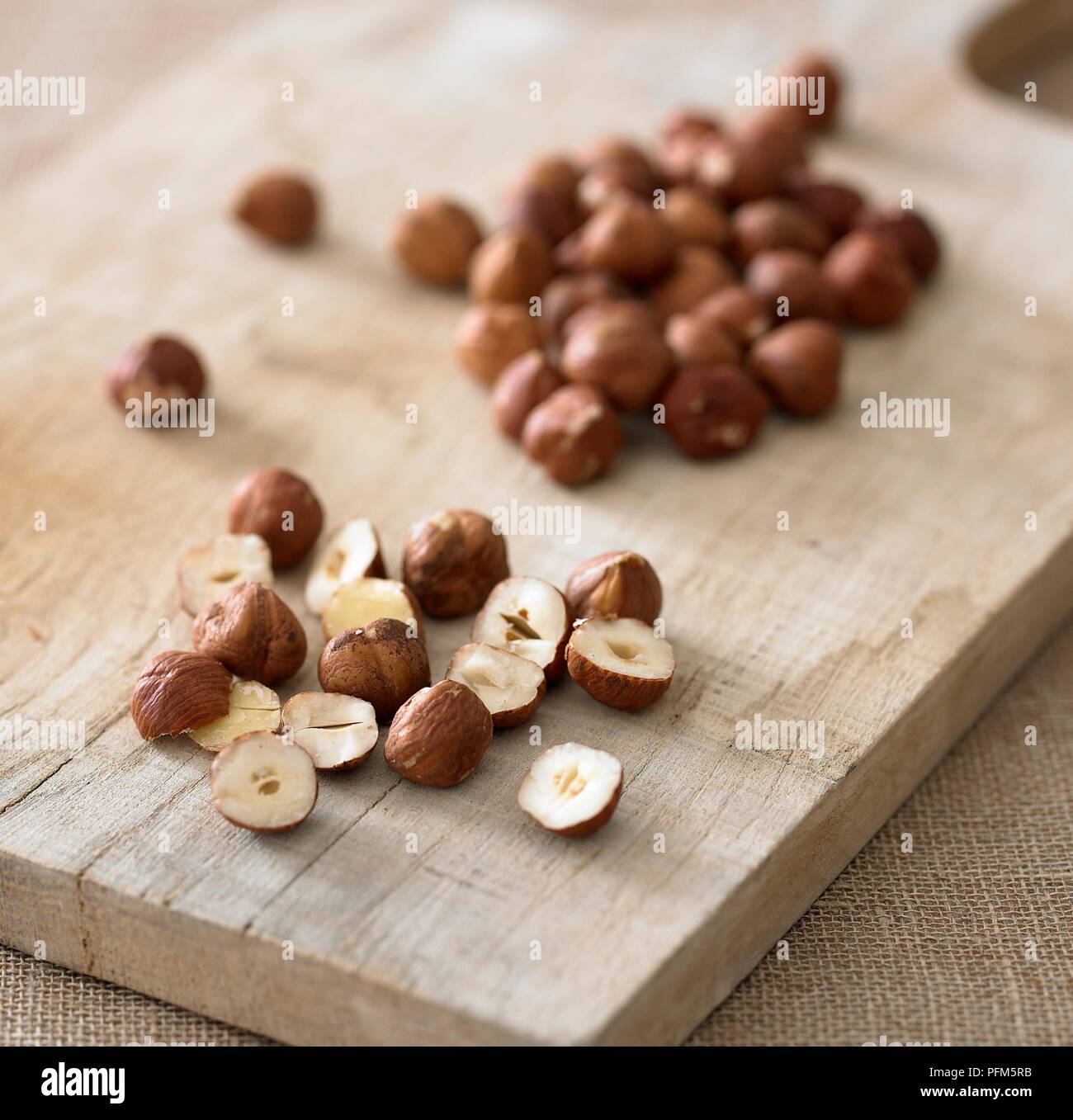 Whole and sliced hazelnuts on chopping board Stock Photo