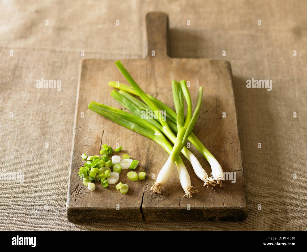 Whole and chopped spring onions on chopping board Stock Photo