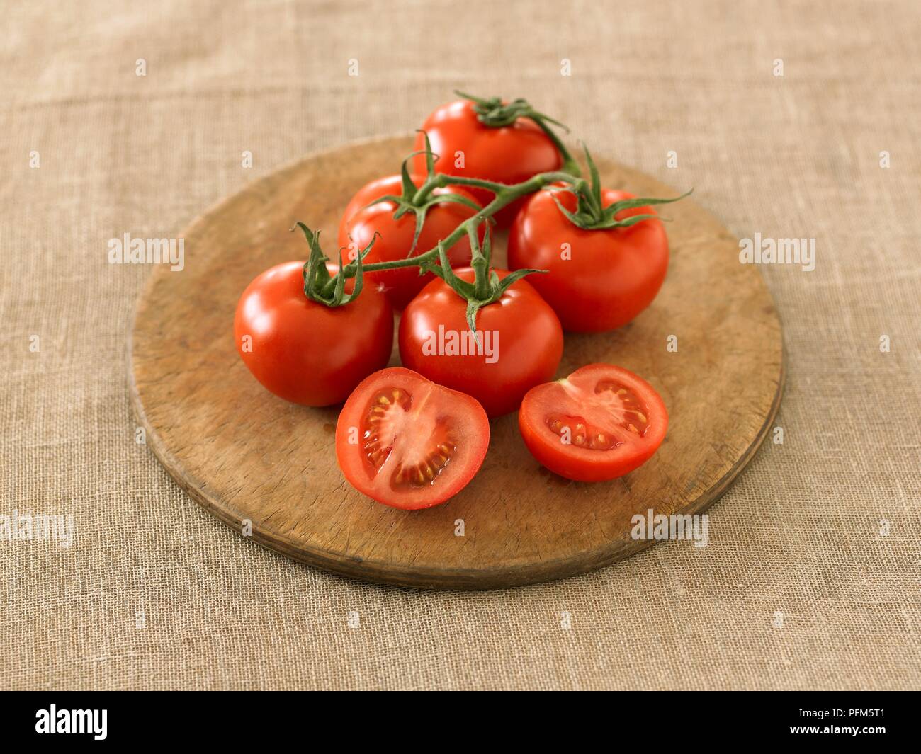 Whole and sliced tomatoes on chopping board Stock Photo