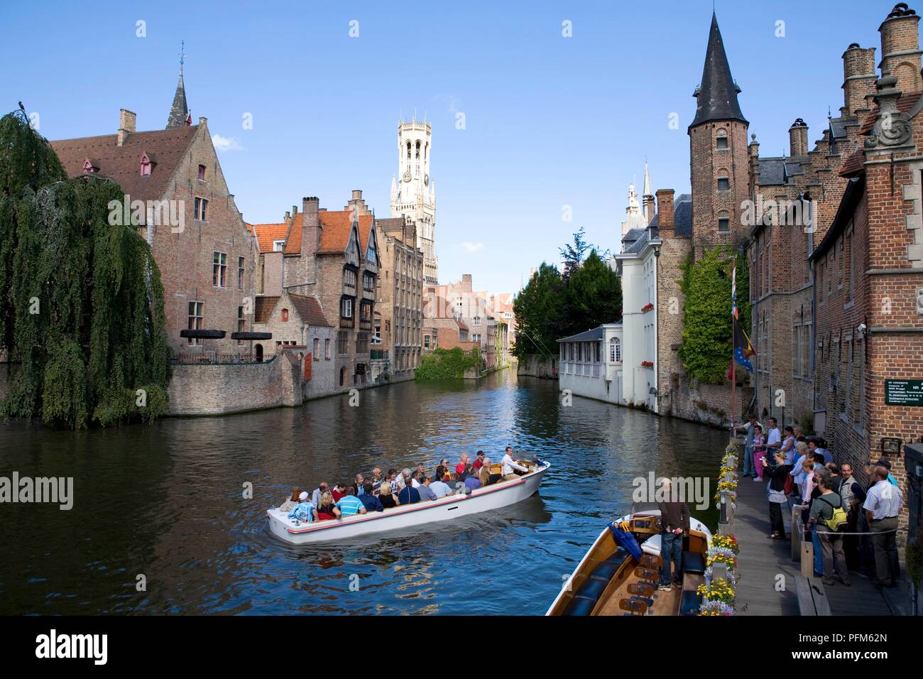 Belgium, Brugge, passengers in boat on canal approaching waterfront Stock Photo