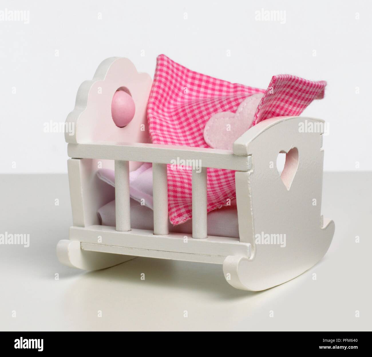 White, wooden toy cot with red gingham blanket Stock Photo