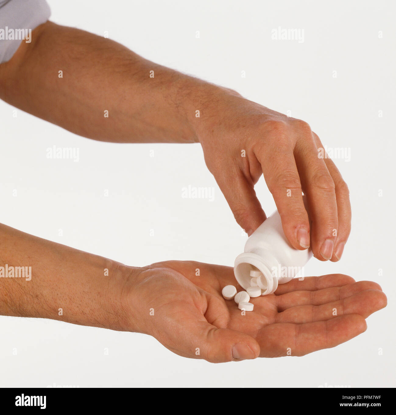 Close-up of one hand pouring white tablets into another hand. Stock Photo