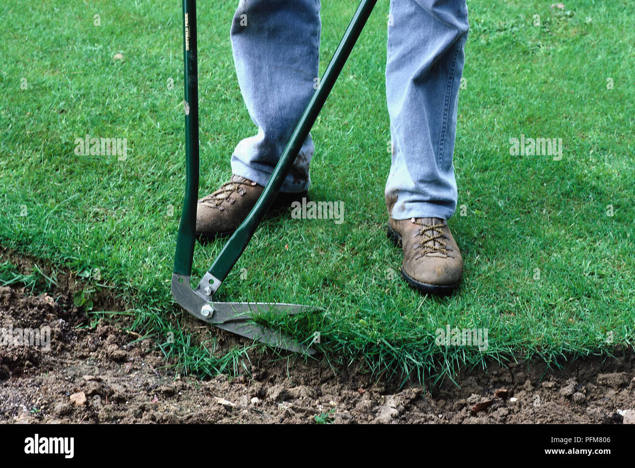 Man trimming the edges of a lawn with long-handled shears. Stock Photo