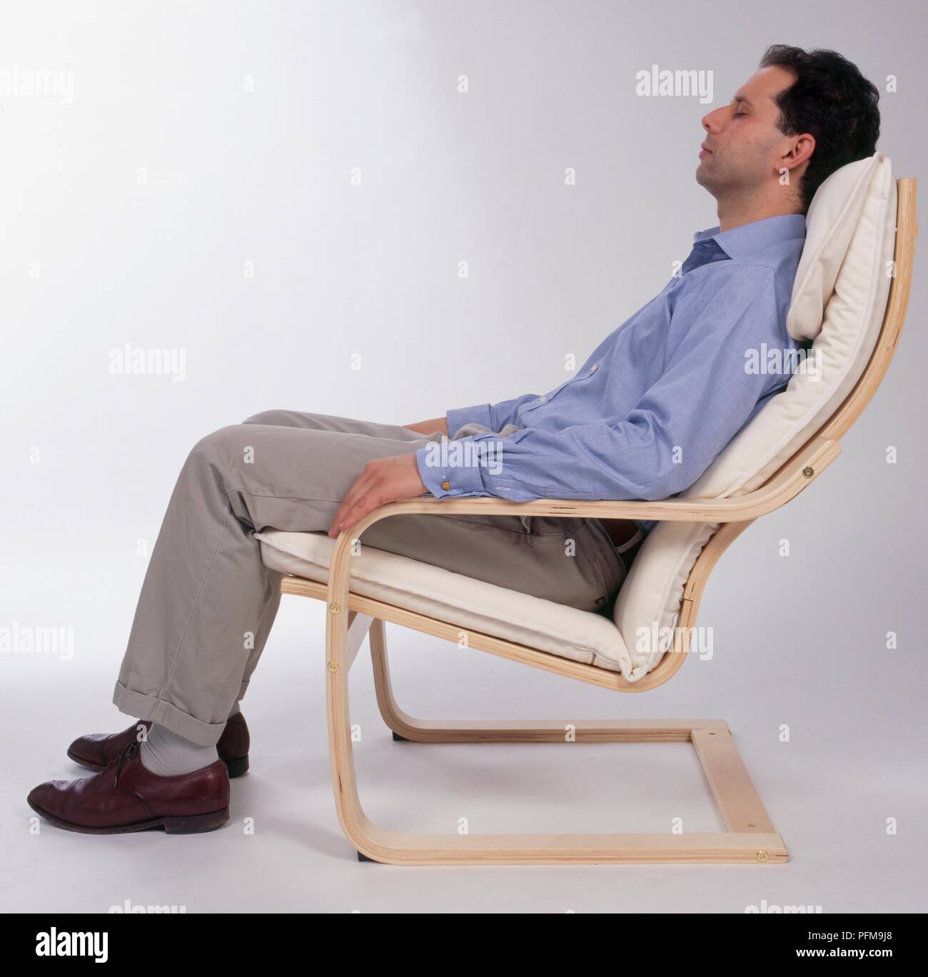 Man sitting reclined in chair with his eyes closed side view Stock