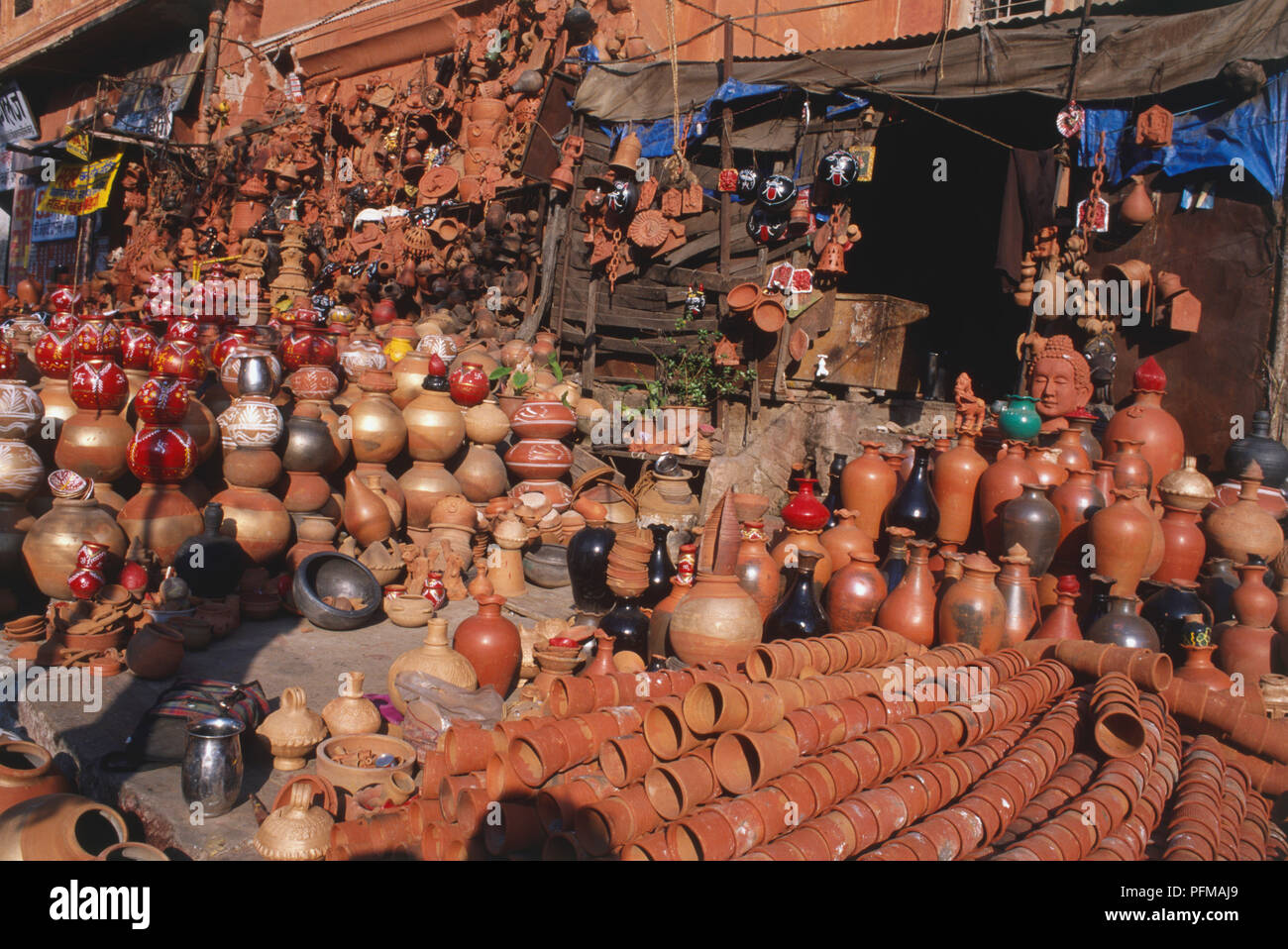 India, attractive terracotta pots on display, for sale outside, wide array of shapes and sizes, some pots painted red, black with white detsil, terracotta flower pots in line, tarpaulin covering some stock. Stock Photo