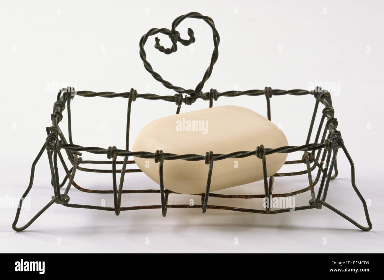 Wire soap rack, heart-shaped design, holding bar of soap. Stock Photo