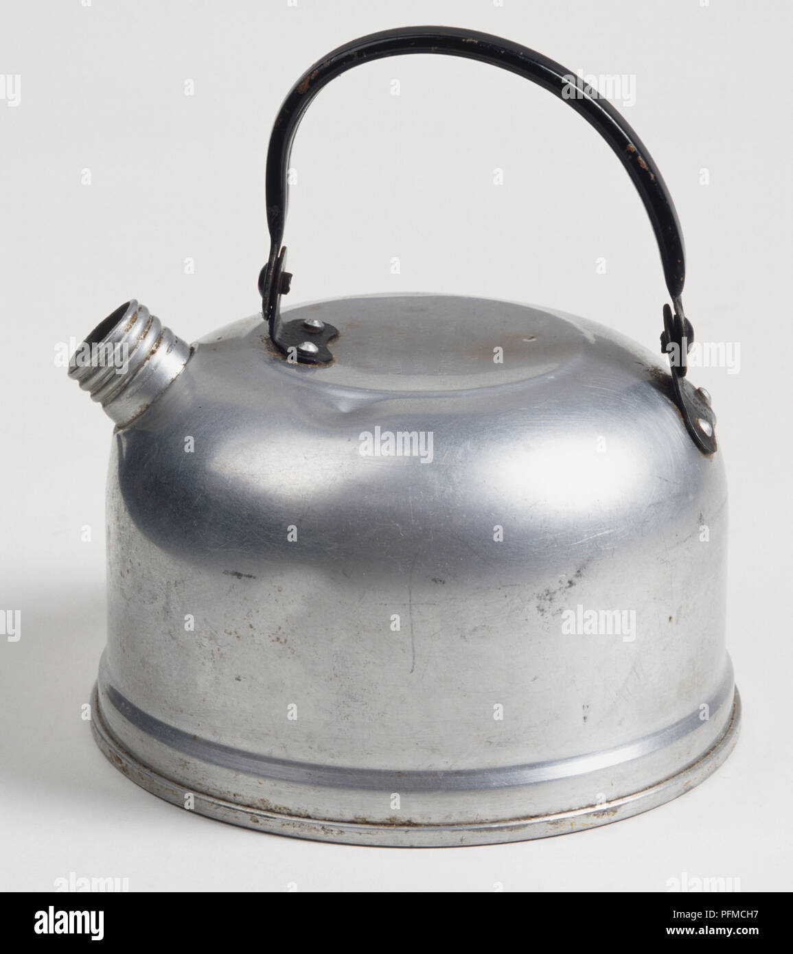 Small camping kettle made of metal, with black handle and short spout, side view. Stock Photo