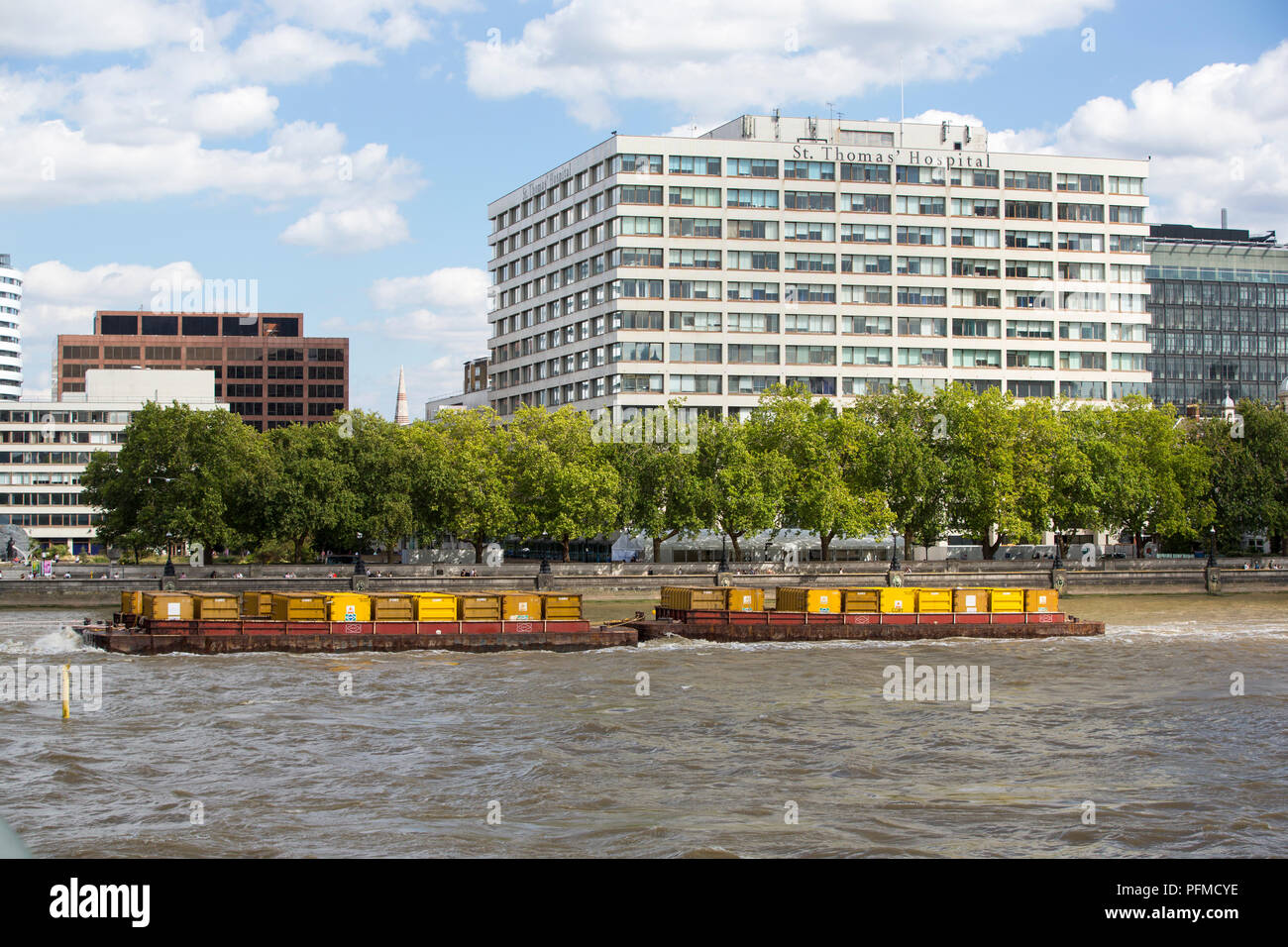 St Thomas's Hospital on the Thames embankment with a barge going down the Thames, London, UK. Stock Photo