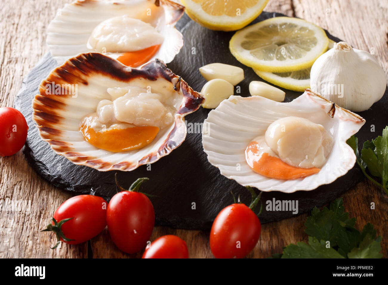 Raw sea scallops in a shell and vegetables for cooking closeup on a