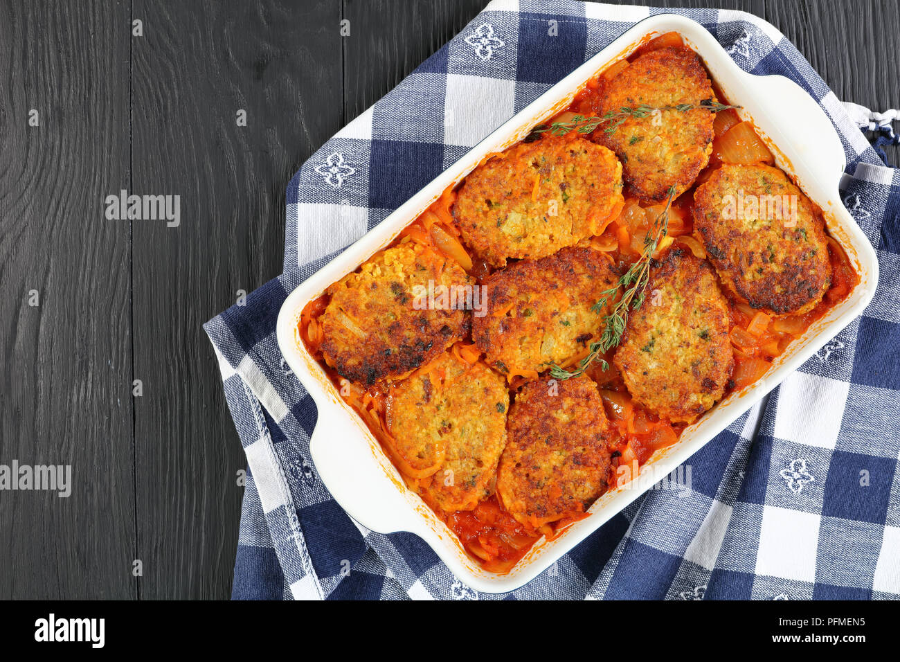 Quick and easy couscous fish patties stewed with onion, carrots and tomato sauce in baking dish, healthy mediterranean recipe, view from above Stock Photo