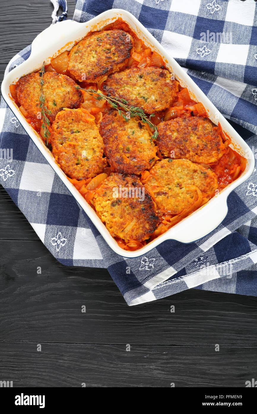 Quick and easy couscous fish patties cooked with onion, carrots and tomato sauce in baking dish, healthy mediterranean recipe, vertical view from abov Stock Photo